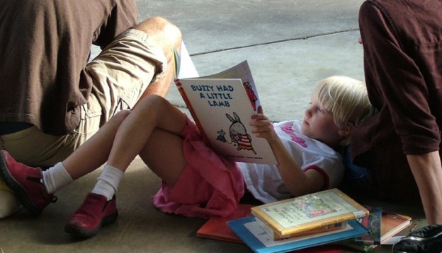 Child waiting for train with story book