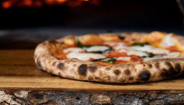 Stonebaked pizza on wood by stove
