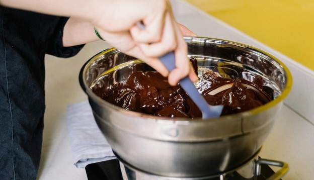 stirring melted chocolate in a metal bowl