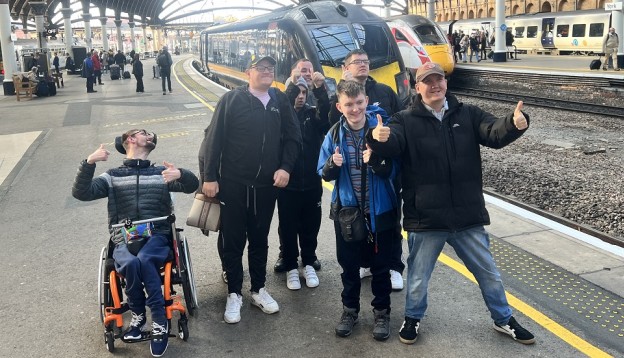 Students smiling for a photo in front of a Grand Central train at York station